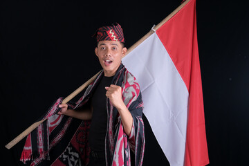 Young man holding the Indonesian national flag welcoming the month of independence on a black background