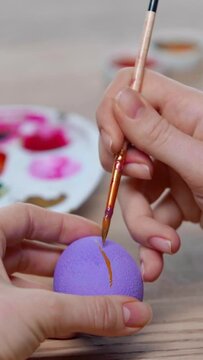 vertical video of cropped woman painting easter egg with paintbrush