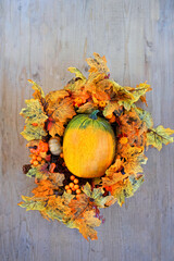 orange ripe pumpkin and decorative bright autumn wreath on wooden background. fall season concept. Symbol of Thanksgiving day, Halloween, Autumn harvest. top view