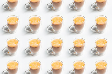 Drink pattern of double walled glass mug with coffee and vegan milk on white background.