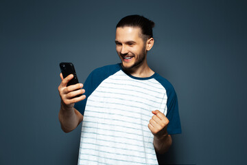 Studio photo of young smiling confident man, holding a smartphone.