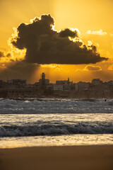 A view of old acre with beautifiul sunlight going through clouds over houses, sea, waves, beach