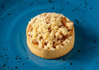 Freshly baked single portion apple pie on a blue porcelain plate