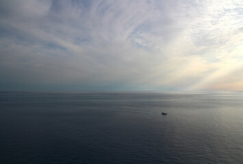 Seen from the heights of Corniglia at the end of an October day (Cinque Terre, Liguria, Italy), a boat returns to port.