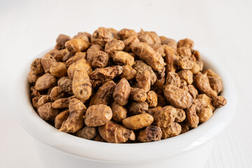 Top view of white bowl with tiger nuts, white blank background, selective focus, horizontal