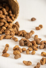 Top view of tiger nuts on white table and basket, selective focus, vertical, with copy space