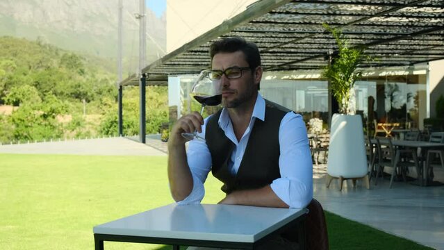Man toasting wineglasses in a luxury restaurant. stylish successful man in a white shirt in a restaurant drinks wine against the backdrop of mountains. male sommelier testing a new variety of wine