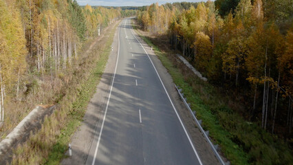 Asphalt road with traffic cars between forest in Ural