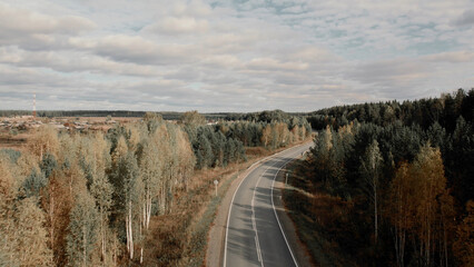 Asphalt road with traffic cars between forest in Ural