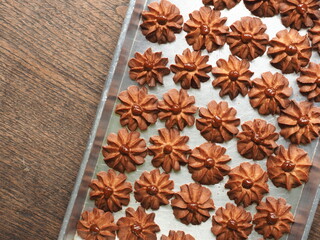 flower shaped cinnamon butter cookies with caramel in baking tray on wooden background