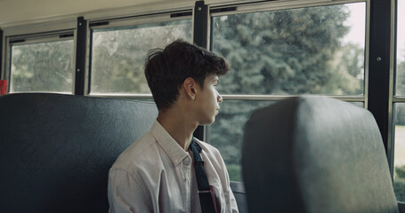Indian teenager boarding schoolbus. Schoolboy with broken arm take seat alone.