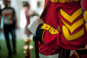 a man dressed as a british guardsman holds a gun in his hand, close-up