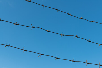 Three rows of barbed wire against the sky