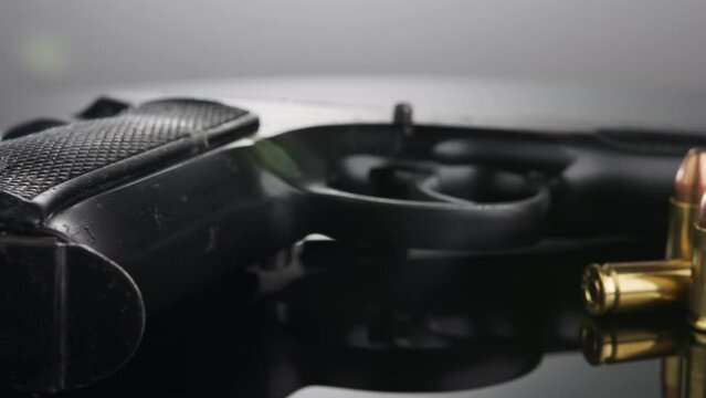 Gun Control. 9mm handgun with bullets rotating on a reflective surface