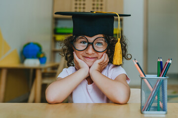 Portrait of happy little girl in graduation mortar hat