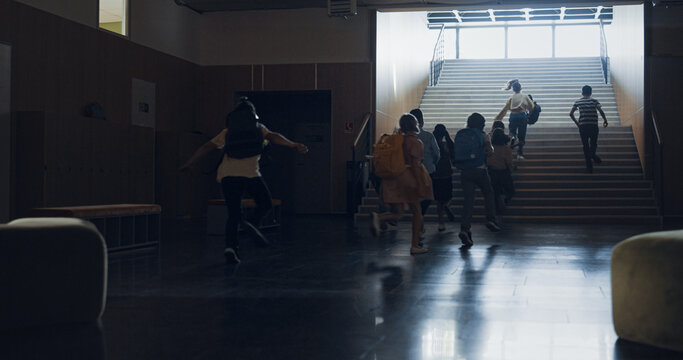 Group pupils running out classroom heading staircase. Teenagers leaving classes. - Powered by Adobe