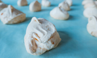 Homemade french milk-colored meringues on blue paper