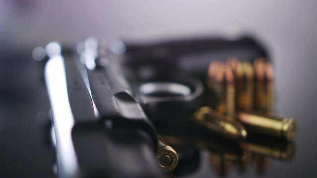 Gun Control. 9mm handgun with bullets rotating on a reflective surface