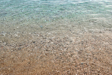 Obraz premium The shore of a pebble beach with clear turquoise water