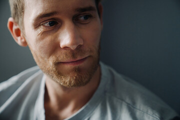Young bearded man wearing t-shirt looking aside at copyspace at home