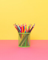 Coloured pencils in green cup. Minimal school concept.