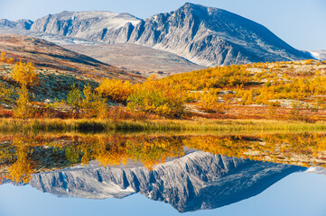 Reflection of mountains and trees in autumn landscape, Norway.