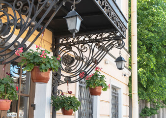 The facade of an old building with decorative elements and flowers in a hanging flowerpot