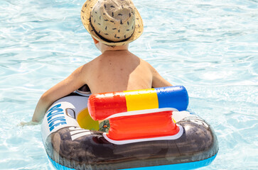 happy joyful little boy having fun in pool water.kid using inflatable ring police car...