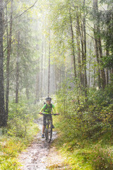 Naklejka premium Boy cycling mountainbike in the rain