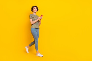Photo of pretty shiny lady wear striped t-shirt walking writing modern device empty space isolated...