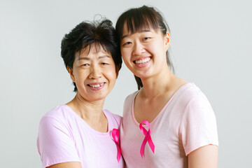 Couple of Asian mother and daughter in pink shirt and pink ribbon for October breast cancer...