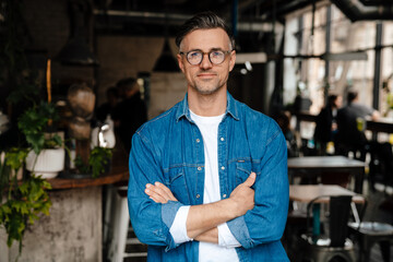 Adult handsome calm man in blue shirt with folded arms