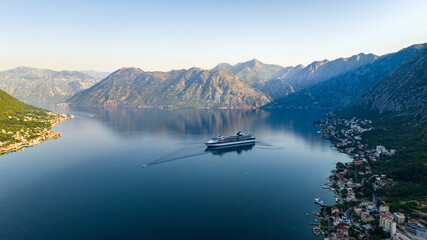 cruise liner in kotor bay during sunrise with mountains on background aerial drone view