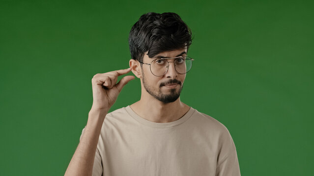 Unhappy arab man disappointed worried hispanic brunet guy isolated standing in green studio making little shape gesture with fingers showing small measure size tiny scale low rating asking less piece