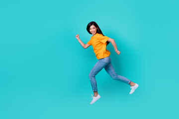 Fototapeta na wymiar Full size photo of sweet brunette lady run wear orange t-shirt jeans sneakers isolated on teal color background