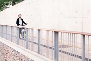 man walking in front of a white wall with his bike