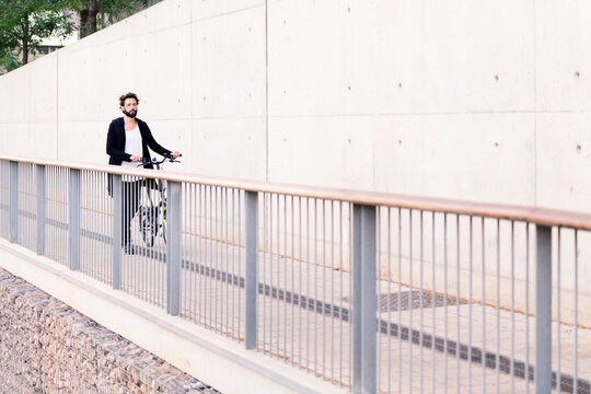 Man Walking In Front Of A White Wall With His Bike