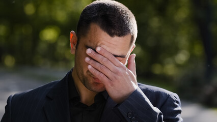 Outdoors portrait sad caucasian hispanic adult 30s business man feel exhaustion stress worry massaging dry irritable eyes suffer from headache eyestrain tired single disappointed upset guy has problem