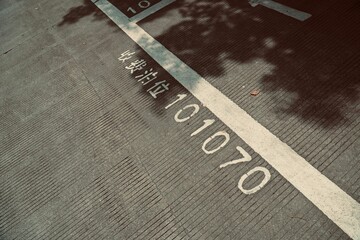 Closeup of an asphalt road with Chinese characters translating 'paid parking lot' and numbers