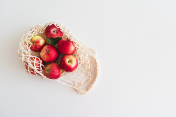 String bag with red ripe apples on white background. Top view