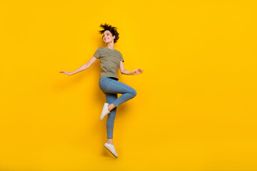 Fototapeta na wymiar Full length photo of sweet shiny lady wear striped t-shirt jumping high looking empty space isolated yellow color background