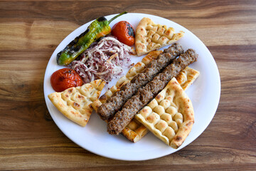 Grilled Turkish Adana, Urfa  Kebab with grilled vegetables, onion and rice on plate. Adana durum.