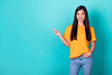 Photo of adorable nice cute girl straight hairdo dressed yellow t-shirt directing empty space arm pocket isolated on teal color background