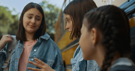 Cute school girl telling funny story to friends close up. Pupil stand at bus.