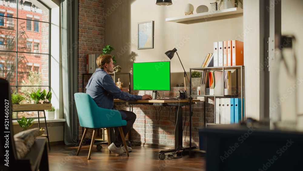 Leinwandbilder young handsome man working from home on desktop computer with green screen mock up display. creative