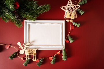 White frame with Christmas decoration with garland and deer figure on a red background