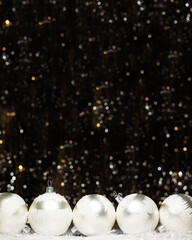 Christmas banner decorations view of five silver evening balls with white snow on it on dark background with silver colors bokeh and artificial snow. Holidays concept with copy space.