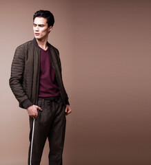 Fototapeta premium young pretty asian man posing in fashion style on light brown background, lifestyle people concept