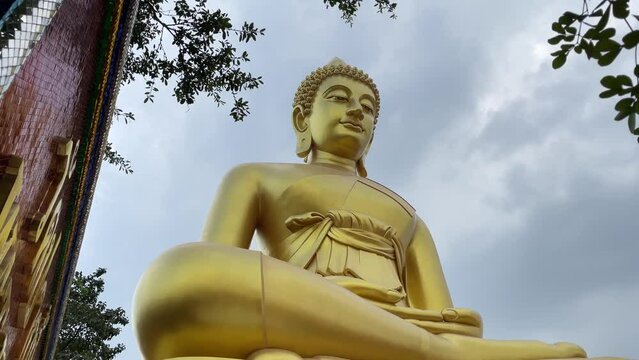 Giant golden buddha statue at Wat Paknam Phasi Charoen, famous buddhist temple with blue sky background - day. BANGKOK, THAILAND 