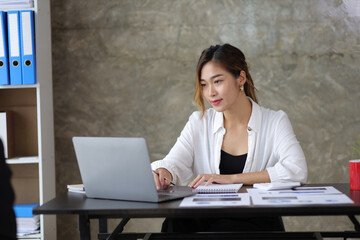 Attractive beautiful Asian business woman working on laptop on desk in office.